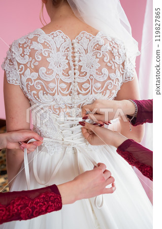 A Close-Up View of a Wedding Dress Being Laced up Before a Ceremony. A Close-Up View of a Wedding Dress Being Laced up Before a Ceremony. 119827865