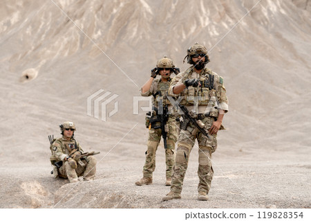 Group of military or soldier with battle suit and carry gun stay relax in area near the mountain during outdoor practice. 119828354