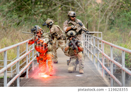 Group of military or soldier team with battle suit stay on the bridge near flare firework in position for battle and point gun different direction during outdoor practice. Group of military or soldier team with battle suit stay on the bridge near flare firework in position for battle and point gun different direction during outdoor practice. 119828355