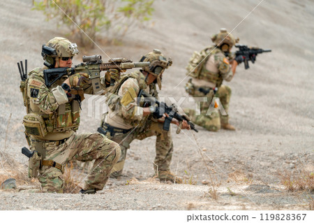 Close up one of soldier or military sit and point gun to the front of enemy with other in his team also point gun the the other direction and ready to fight. 119828367