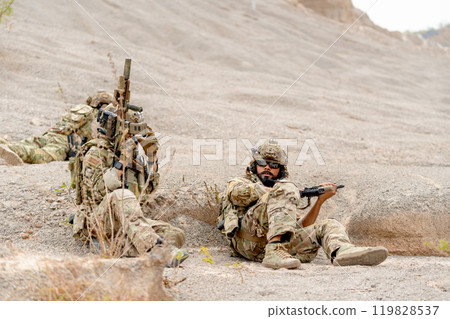 Two of military or soldiers with hold the gun stay low with lie and sit near the moutain during practice for fighting outdoor. 119828537