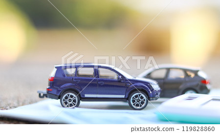 Model car and calculator are on notebook with blur background. Planning of saving for buying car, car loan and car insurance concept. Model car and calculator are on notebook with blur background. Planning of saving for buying car, car loan and car insurance concept. 119828860