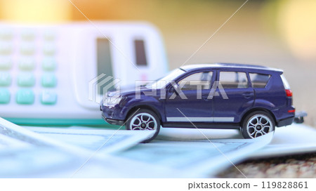 Model car and calculator are on notebook with blur background. Planning of saving for buying car, car loan and car insurance concept. Model car and calculator are on notebook with blur background. Planning of saving for buying car, car loan and car insurance concept. 119828861