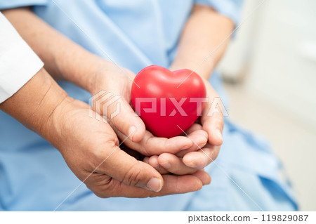 Asian elder senior woman patient holding red heart in hospital. 119829087