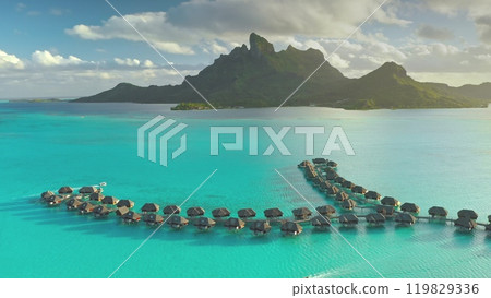 Overwater bungalows resort lining up turquoise blue lagoon of Bora Bora island in French Polynesia. Popular tourist destination. Remote wild nature paradise, exotic summer travel, romantic honeymoon Overwater bungalows resort lining up turquoise blue lagoon of Bora Bora island in French Polynesia. Popular tourist destination. Remote wild nature paradise, exotic summer travel, romantic honeymoon 119829336