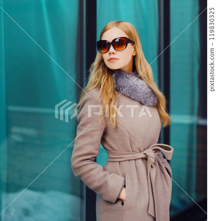 Fashion beautiful blonde woman wearing a coat jacket and sunglasses in city 119830325