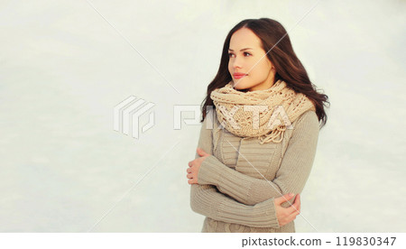Beautiful young woman wearing a knitted sweater and scarf in winter day looking away profile view Beautiful young woman wearing a knitted sweater and scarf in winter day looking away profile view 119830347