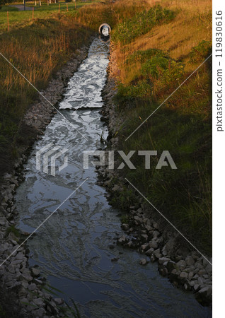 a small drainage or irrigation ditch with stagnant water flowing through it 119830616