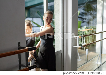 Medium full shot of tired looking young ballerina walking into practice room at start of dance class in studio, copy space Medium full shot of tired looking young ballerina walking into practice room at start of dance class in studio, copy space 119830839