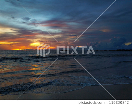 Calm ocean waves on a deserted beach with black volcanic sand. Beautiful sunset on the horizon Calm ocean waves on a deserted beach with black volcanic sand. Beautiful sunset on the horizon 119830842