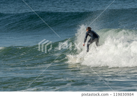Surfer riding a wave on an Atlantic Ocean beach. 119830984