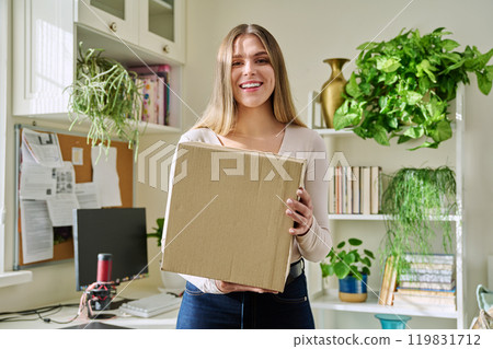 Young woman at home unpacks cardboard box with online purchases Young woman at home unpacks cardboard box with online purchases 119831712