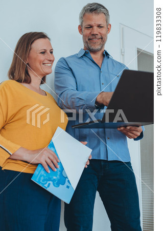 Man and woman smiling professional business people talking using laptop computer working in office.  119833308