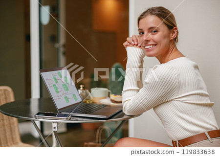 A Smiling Woman Engaged in Working on Her Laptop Within a Modern Workspace Environment A Smiling Woman Engaged in Working on Her Laptop Within a Modern Workspace Environment 119833638