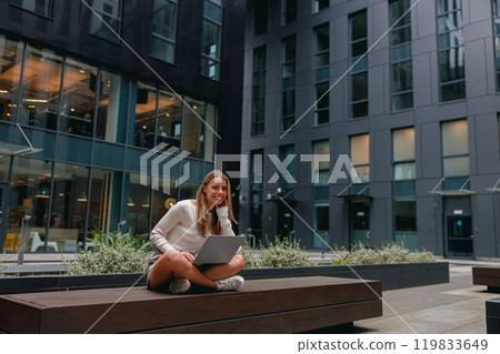 A Young Woman Engaged in Productive Work on Her Laptop in a Contemporary Urban Environment A Young Woman Engaged in Productive Work on Her Laptop in a Contemporary Urban Environment 119833649