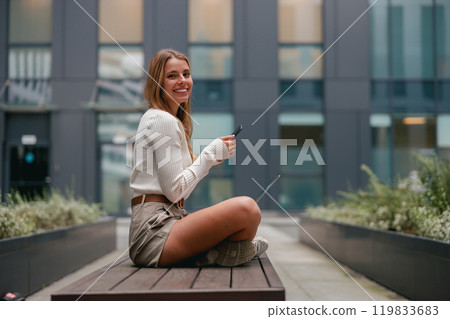 A young woman delightedly enjoying her coffee in a modern urban setting that is vibrant and lively A young woman delightedly enjoying her coffee in a modern urban setting that is vibrant and lively 119833683