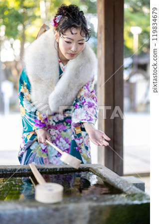 A young woman in formal attire praying at a shrine 119834679