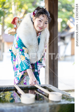 A young woman in formal attire praying at a shrine A young woman in formal attire praying at a shrine 119834684
