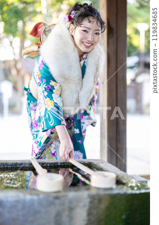 A young woman in formal attire praying at a shrine A young woman in formal attire praying at a shrine 119834685