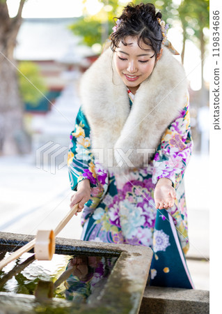 A young woman in formal attire praying at a shrine A young woman in formal attire praying at a shrine 119834686