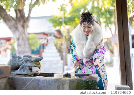 A young woman in formal attire praying at a shrine 119834690
