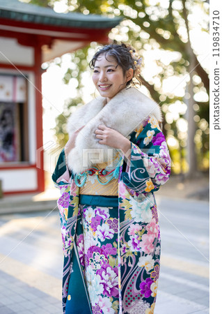 A young woman in formal attire praying at a shrine 119834710