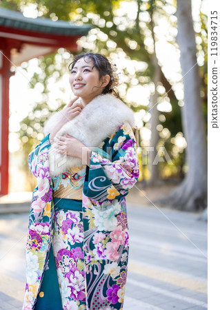A young woman in formal attire praying at a shrine 119834715