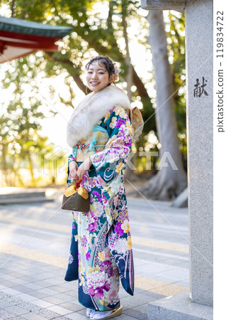 A young woman in formal attire praying at a shrine 119834722