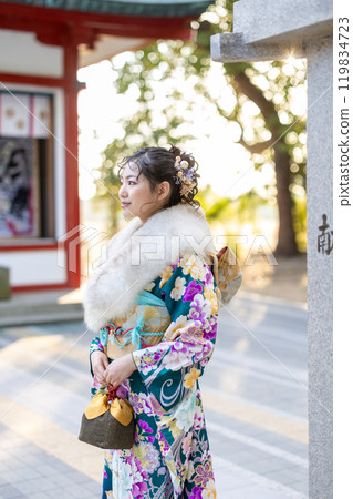 A young woman in formal attire praying at a shrine 119834723