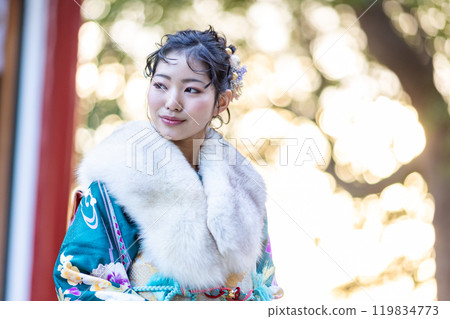 A young woman in formal attire praying at a shrine 119834773