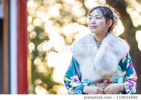 A young woman in formal attire praying at a shrine 119834800