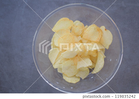 Enjoy a delightful serving of freshly made potato chips presented attractively in a clear bowl 119835242