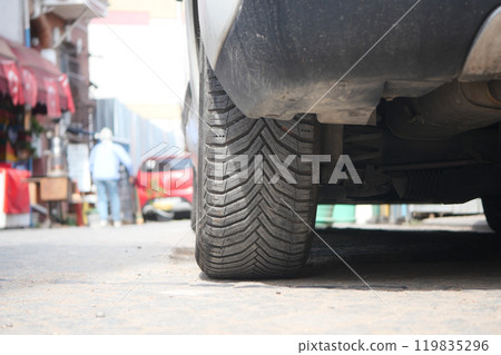 This is a closeup view of a car tire resting on a city street, providing intricate details This is a closeup view of a car tire resting on a city street, providing intricate details 119835296