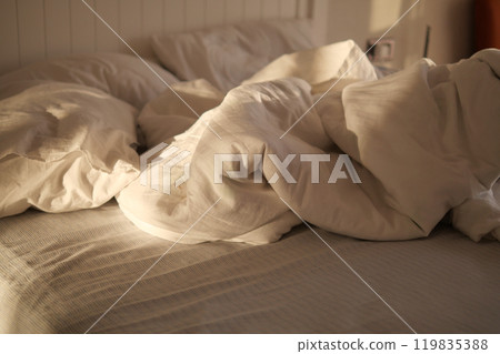 A disheveled bed adorned with vibrant, colorful floral bedding and a striking green headboard A disheveled bed adorned with vibrant, colorful floral bedding and a striking green headboard 119835388