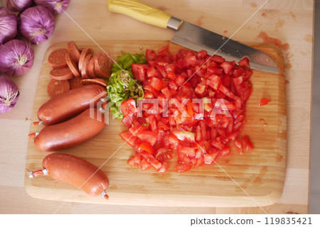 Chopped and beautifully arranged colorful vegetables along with sausages on a Wooden Cutting Board Chopped and beautifully arranged colorful vegetables along with sausages on a Wooden Cutting Board 119835421