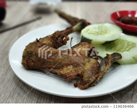 A plate of traditional fried chicken with a side of cucumber slices and a traditional chili paste. 119836466