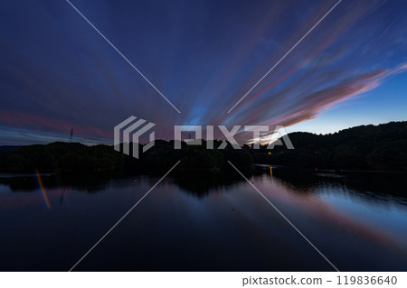 Mid-autumn evening view of Nunome Dam in the Yamato Plateau in the eastern part of Nara City. Sunset on the mountainside and crimson clouds floating in the blue sky. 119836640