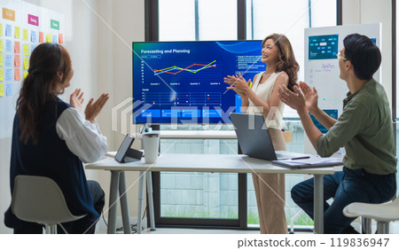 group of investor celebrating a successful outcome in a modern office clapping hand  in front of a digital screen displaying financial data 119836947