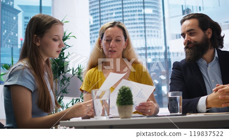 Parent and child looking over personalized planning guide written by financial advisor during meeting. Consultant optimizing spending habits of clients requesting help, camera A 119837522