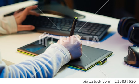 Photo editor using graphic tablet to edit color balance, delivering appealing photographs for magazines. Close up on graphic designer using stylus on touchscreen device to modify images, camera A 119837620