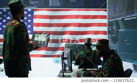 US soldiers operating in a high tech cybersecurity command post, managing state secrets and classified information. Protecting servers against digital threats and cyber warfare. Camera B. US soldiers operating in a high tech cybersecurity command post, managing state secrets and classified information. Protecting servers against digital threats and cyber warfare. Camera B. 119837622