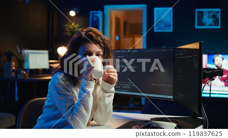 Portrait of happy computer engineer enjoying hot tea while implementing security measures to protect company systems and data. Joyful IT worker holding coffee mug and debugging code, camera B Portrait of happy computer engineer enjoying hot tea while implementing security measures to protect company systems and data. Joyful IT worker holding coffee mug and debugging code, camera B 119837625