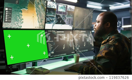 Military agent working in control room, using software on green screen devices, analyzing aerial reconnaissance data. Intelligence corps expert controlling drones with chroma key systems, camera B 119837626