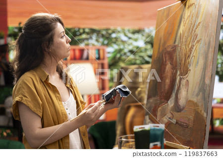 Painter using a piece of fabric to clean her paintbrush and change the color of the painting, using modern art supplies and tool for beautiful masterpiece. Creative woman with skill uses watercolor. 119837663