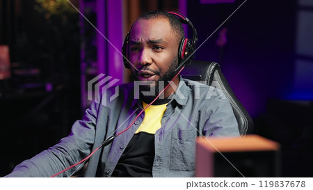 Man having fun playing videogames on PC, putting on headset to chat with teammates. Gamer battling rival players online, communicating with friends through headphones, camera A Man having fun playing videogames on PC, putting on headset to chat with teammates. Gamer battling rival players online, communicating with friends through headphones, camera A 119837678