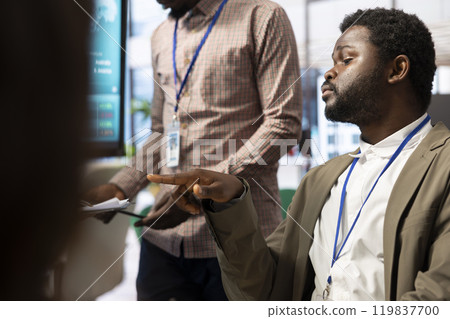 Diverse work team gathers to examine project progress in a briefing meeting, utilizing detailed reports and smart technology to ensure strategic goals achievement and successful execution. 119837700