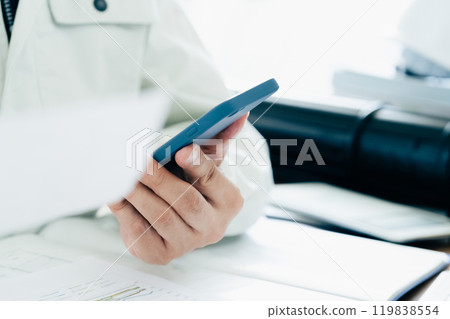 一名穿著工作服的男子正在操作智慧型手機 一名穿著工作服的男子正在操作智慧型手機 119838554