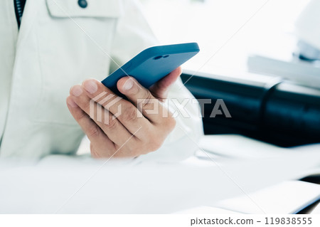 一名穿著工作服的男子正在操作智慧型手機 一名穿著工作服的男子正在操作智慧型手機 119838555