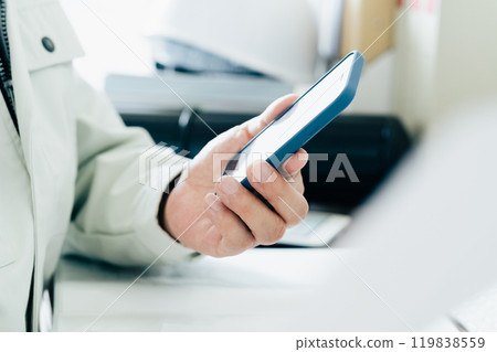 A man in work clothes operating a smartphone 119838559