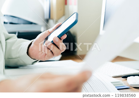 A man in work clothes operating a smartphone 119838560